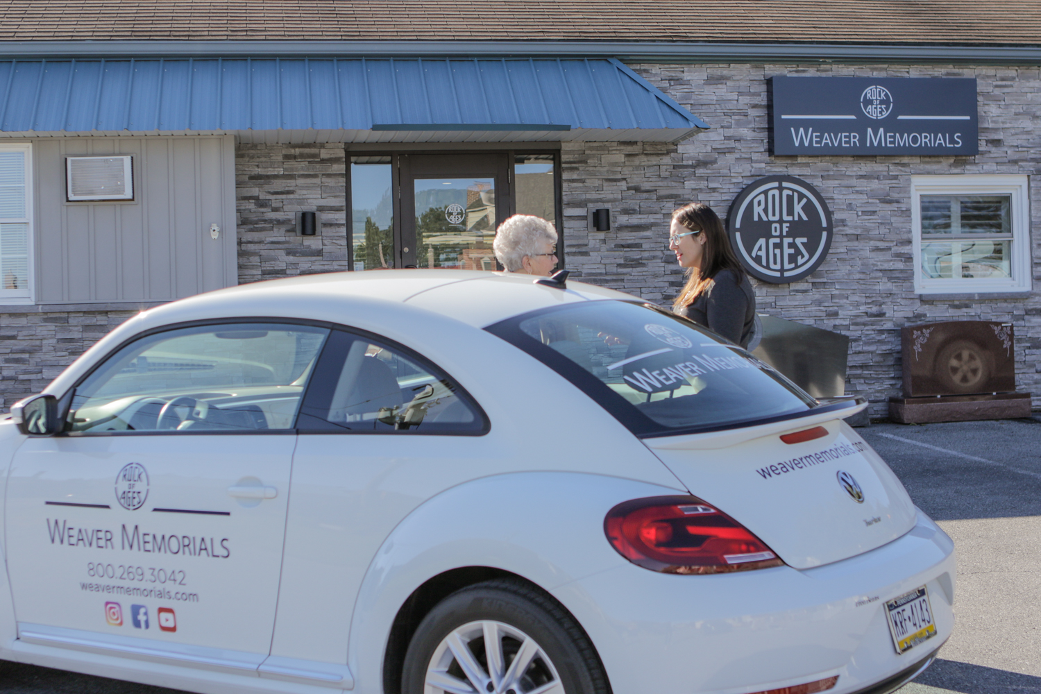 Weaver Memorials transportation vehicle in front of showroom while two women talk